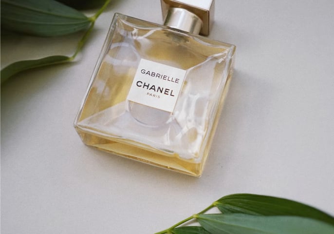 A bottle of perfume surrounded by foliage